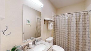 Baño con lavamanos, inodoro y cortina de ducha.