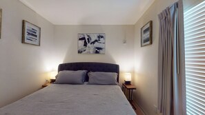 Un dormitorio con una cama, dos lámparas de noche, una mesita de noche y un cuadro abstracto en la pared.