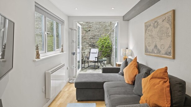 Ein modernes Wohnzimmer mit einem grauen Sofa, einer Karte an der Wand und Blick ins Freie.
