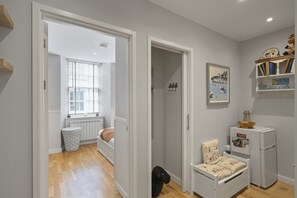 A hallway with a bed, a radiator, a window, and a bookshelf. - Apartment in Grade II Listed Building, Dartmouth (Devon)