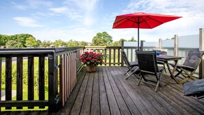 A wooden deck with a table and chairs, a red umbrella, and a potted plant. - Apartment 'Ferienwohnung Windrose' with Private Terrace and Wi-Fi (Pellworm)