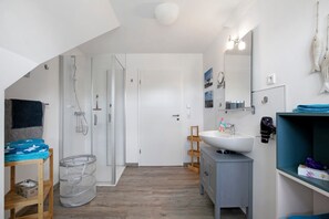 Moderni kylpyhuone, jossa on suihku, pesuallas ja peili.