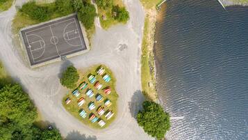 Enjoy outdoor activities in a serene natural setting with a basketball court, boats, and a scenic pathway to the water's edge.