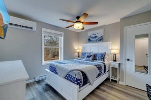 Un dormitorio con una cama, un ventilador de techo, una ventana y una puerta.