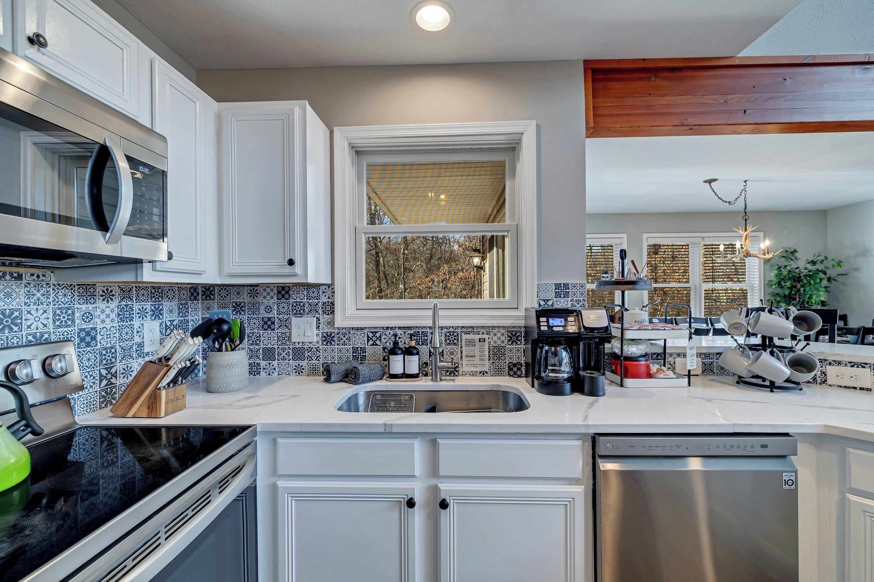 Cocina moderna con armarios blancos, lavavajillas de acero inoxidable, microondas integrado y una estación de café.