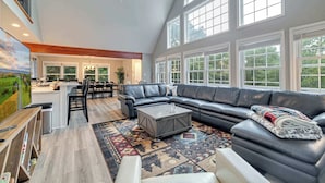 A spacious living room with a large sectional sofa, a coffee table, and a dining area in the background. - Hot Tub, Game Room, Dog Friendly, Sports Bar, A/C (Albrightsville)