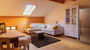 Un espai loft acollidor amb sostre de fusta, un sofà blanc, una taula de dinar i un moble amb portes de vidre.