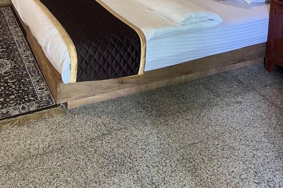 A neatly made bed with a quilted cover, a wooden headboard, and two bedside tables with lamps.
