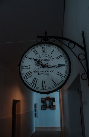 Un reloj grande y ornamentado con números romanos y la inscripción "Victoria Station Railway Clock London" en su esfera, montado en una pared en un pasillo.