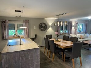Una cocina moderna con una isla central, comedor con sillas y un espacio de sala con sofá.