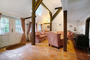 A cozy living room with a fireplace, checkered sofas, and a tiled floor.