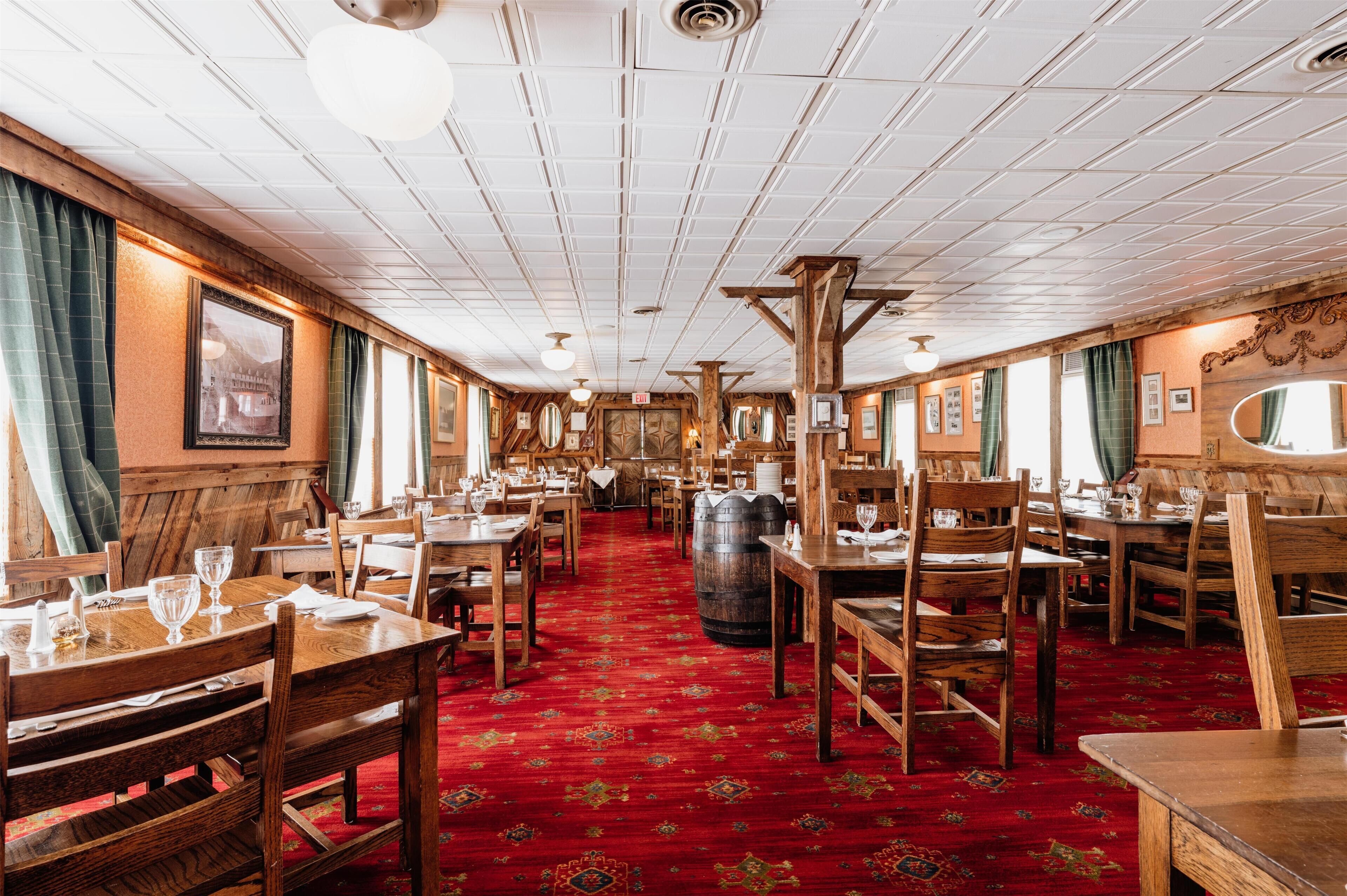 Un restaurant avec des tables et des chaises en bois, une moquette rouge et un plafond en bois.