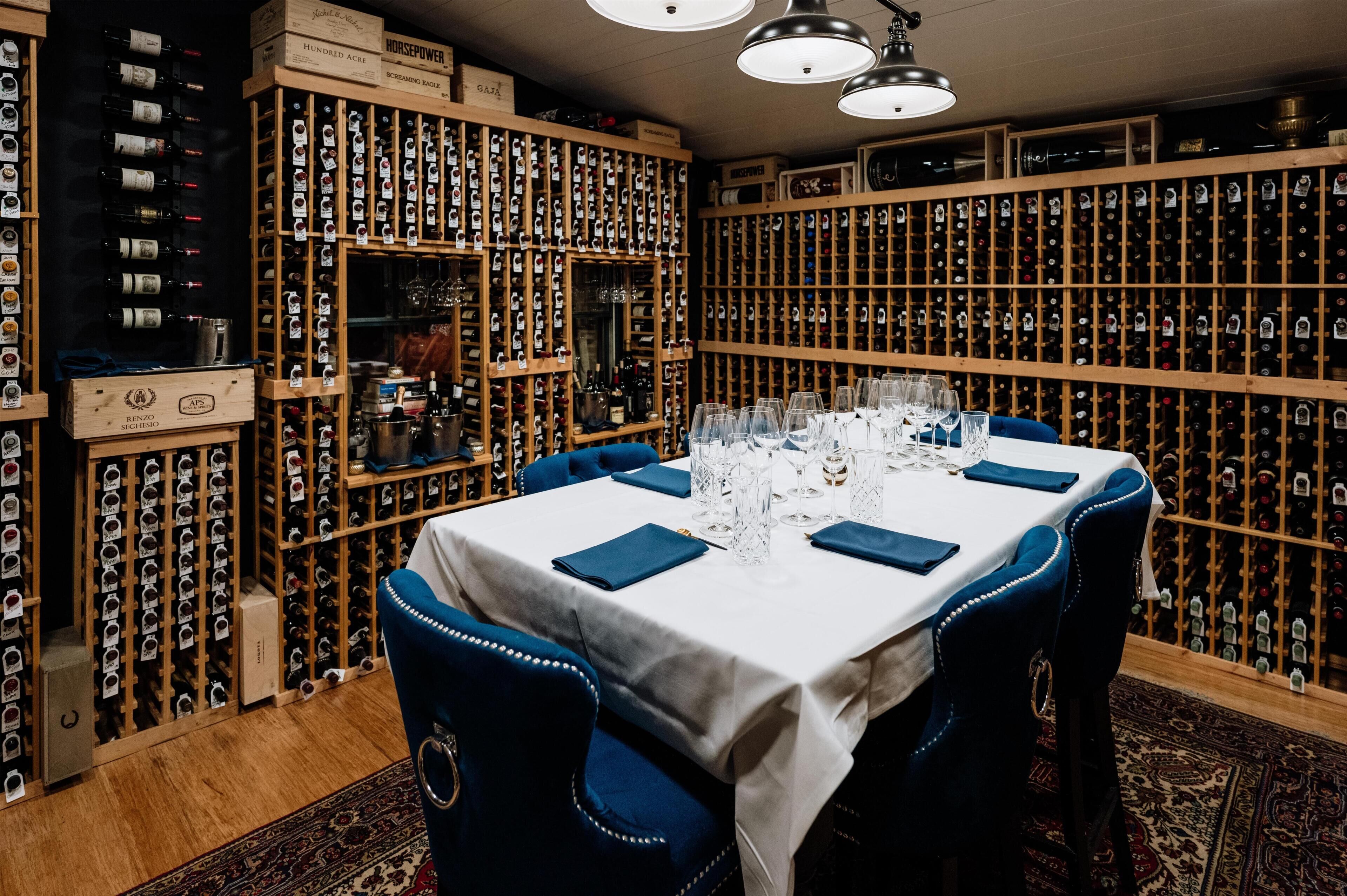 A wine cellar with rows of wine bottles and a table set for dining.