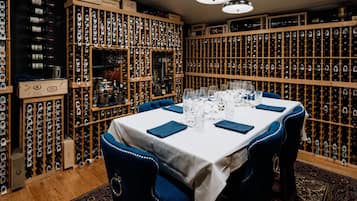 A wine cellar with rows of wine bottles and a table set for dining.