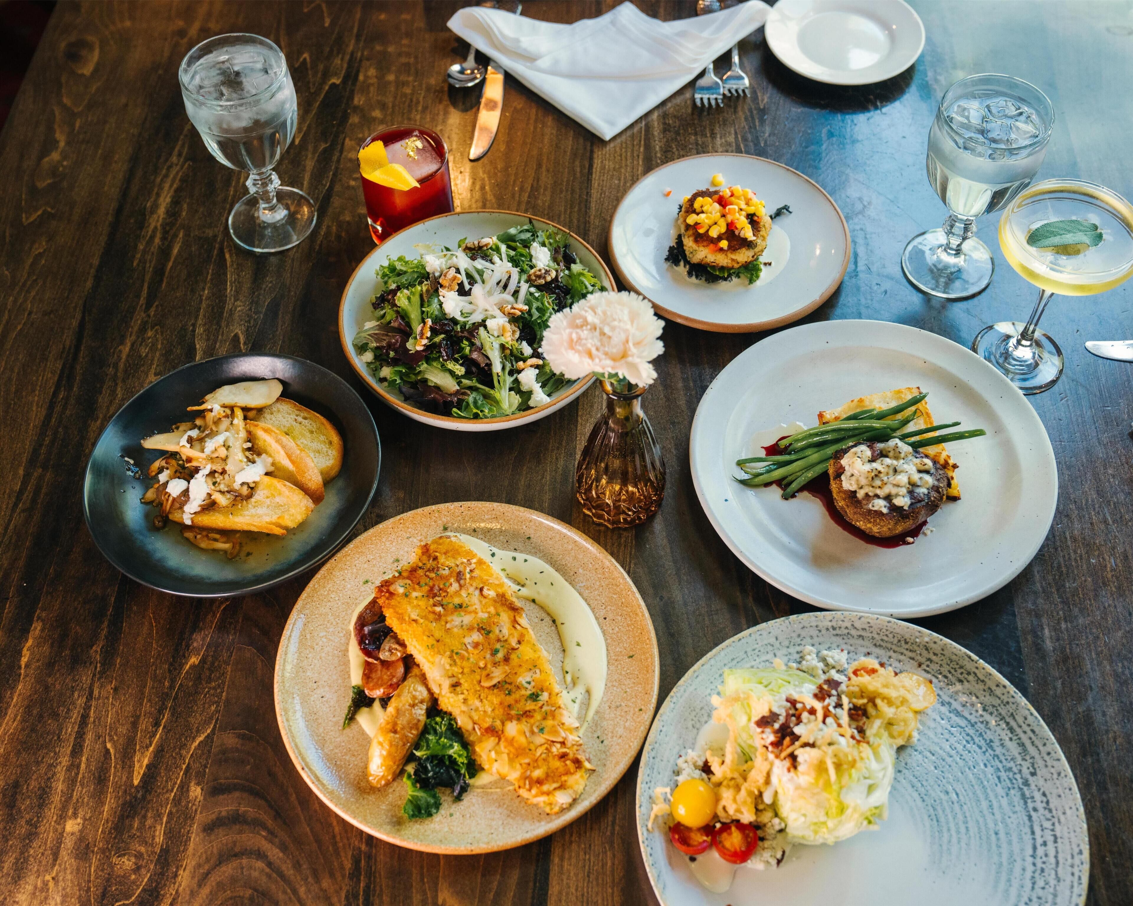 A table with various dishes, including a fish fillet, salad, and a dessert.