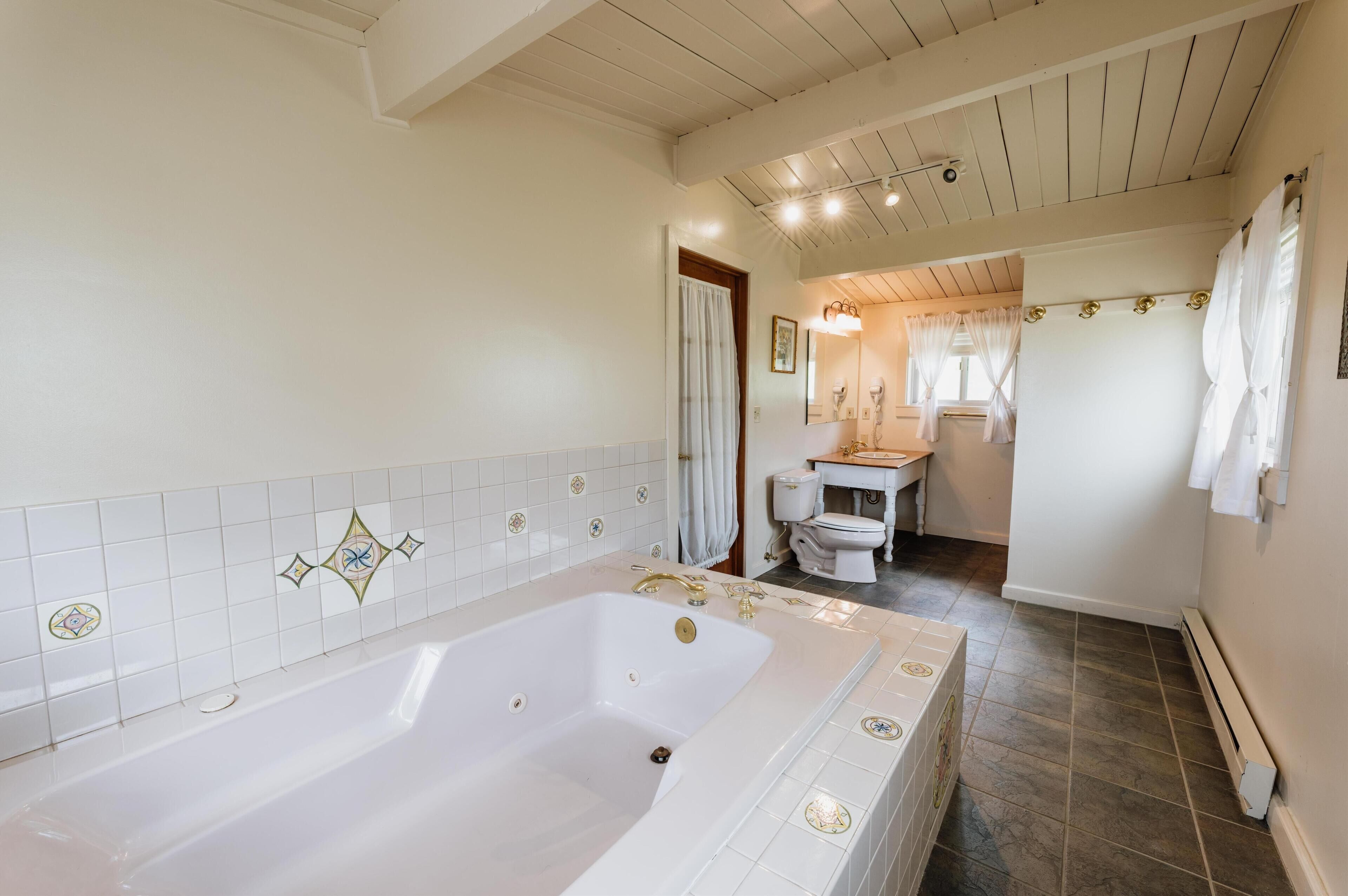 A bathroom with a large bathtub, a toilet, and a sink.