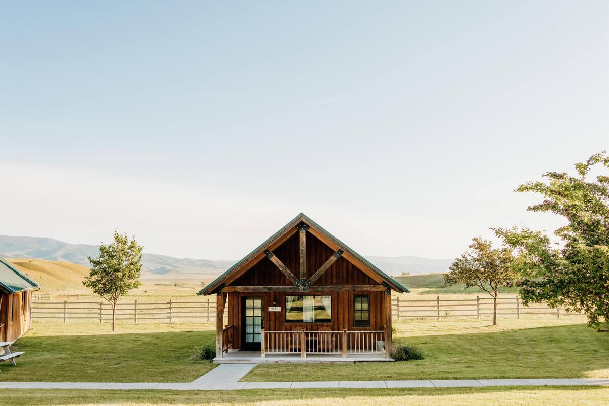 A rustic cabin with a wooden exterior, a front porch, and a clear view of the surrounding landscape.