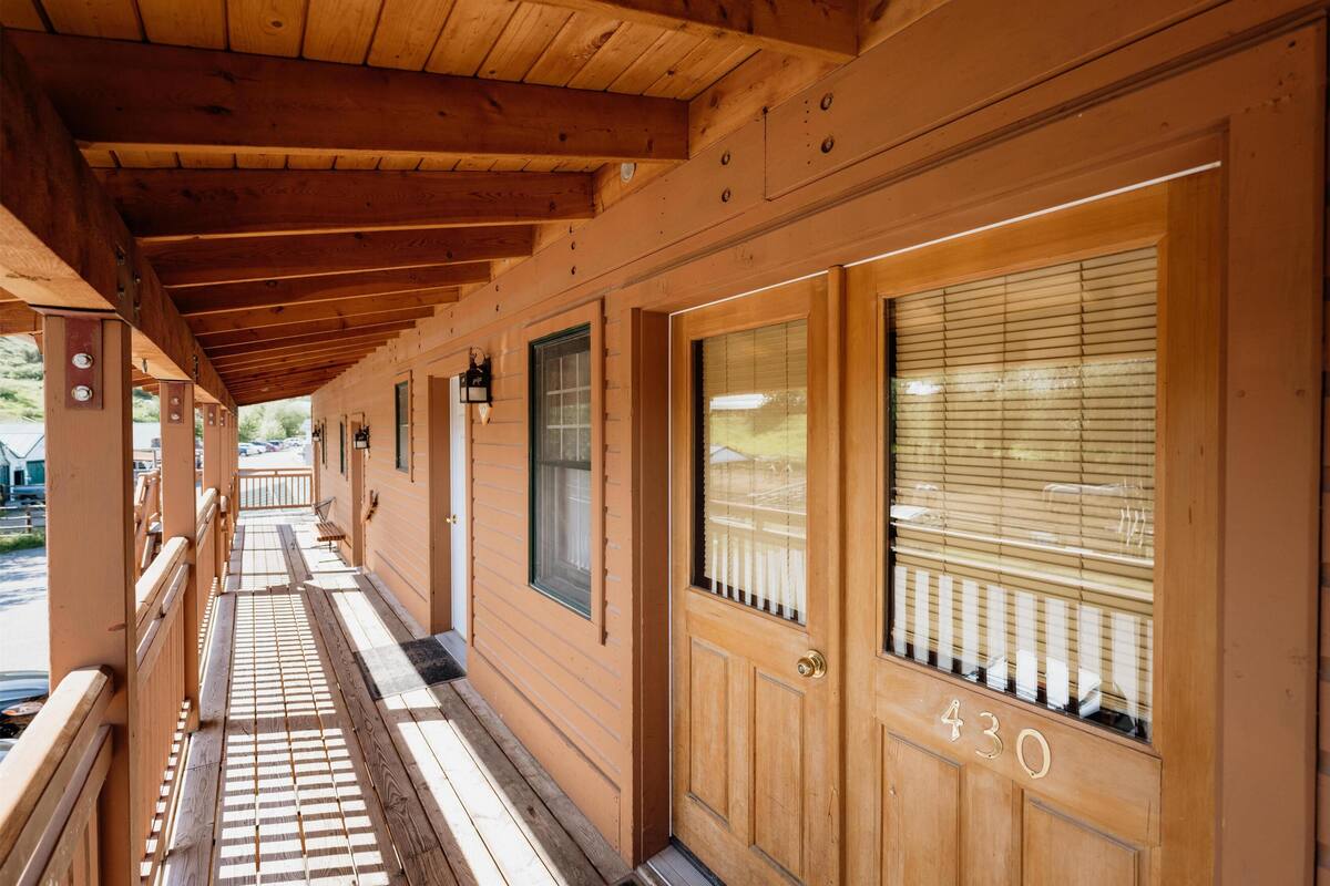 A wooden building with a covered porch, a door labeled "430", and a window with blinds.