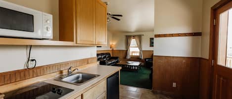 A compact kitchen with wooden cabinets, a microwave, a sink, and a dishwasher.