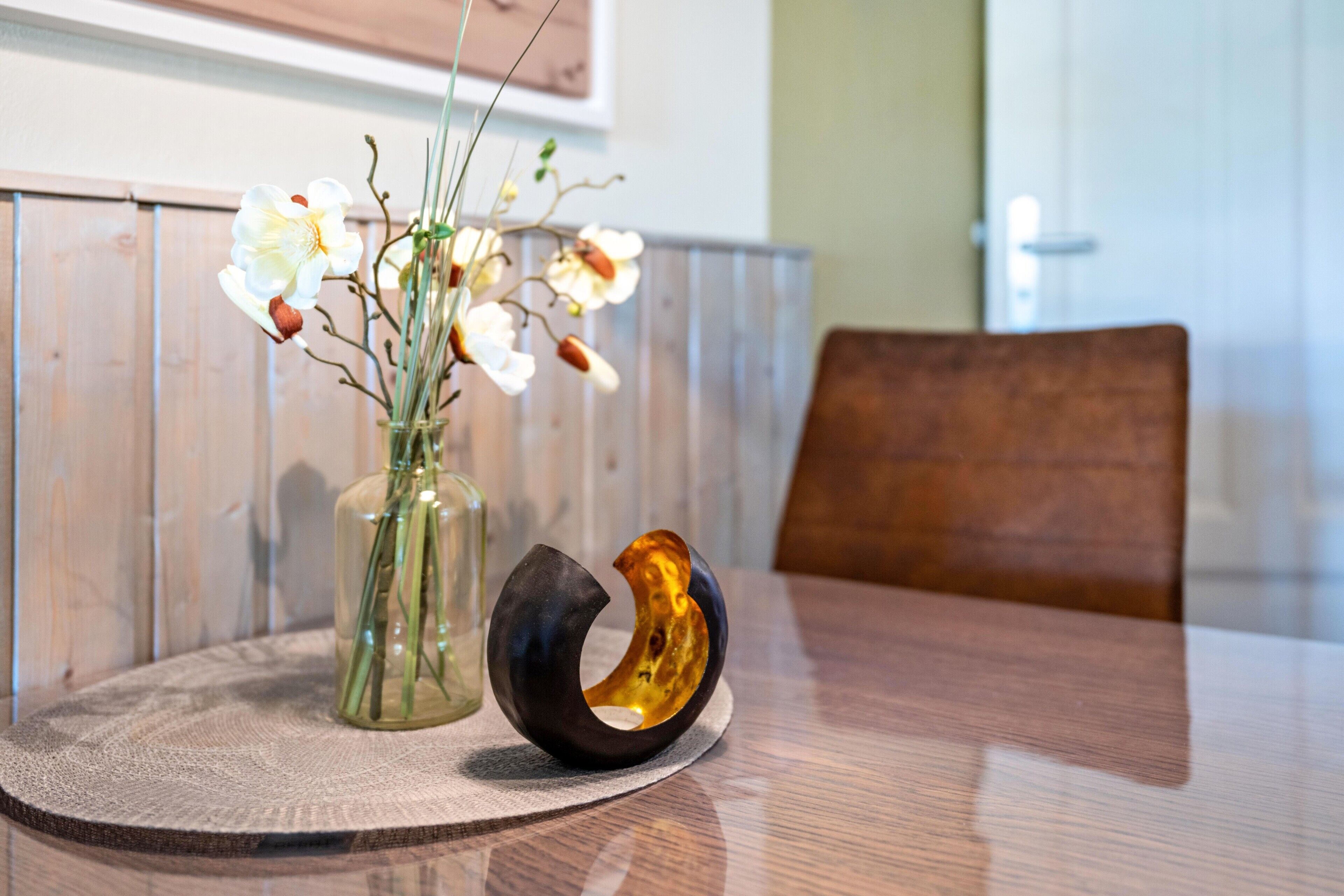 Una mesa redonda con un florero y un cuenco decorativo.