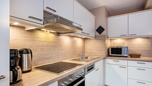 Una cocina moderna con electrodomésticos de acero inoxidable, un lavamanos doble y armarios blancos.