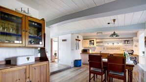 A kitchen with wooden cabinets, a dining table with chairs, and a microwave. - Holiday Home 'Pellworm-Kate' with Private Terrace, Private Garden and Wi-Fi (Pellworm)