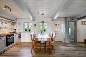 A kitchen with a dining table, chairs, and a window. - Holiday Home 'Pellworm-Kate' with Private Terrace, Private Garden and Wi-Fi (Pellworm)