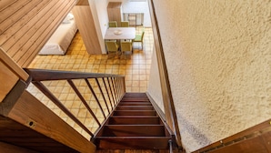 Una escalera de madera que conduce a una habitación con cama, una mesa y sillas.
