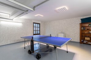A ping pong table in a room with a bookshelf and a window.