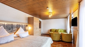Een hotelkamer met een bed, een groene bank, een flatscreen televisie en een muurschildering.