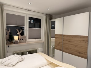 Una camera da letto con un letto, una finestra con persiane, un termosifone e un armadio.