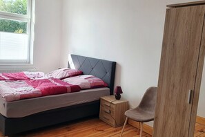 A bedroom with a bed, a bedside table, a chair, and a wardrobe.