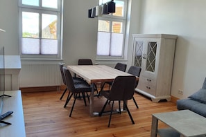 Un coin repas avec une table et des chaises en bois, un meuble avec des portes en verre et un canapé.