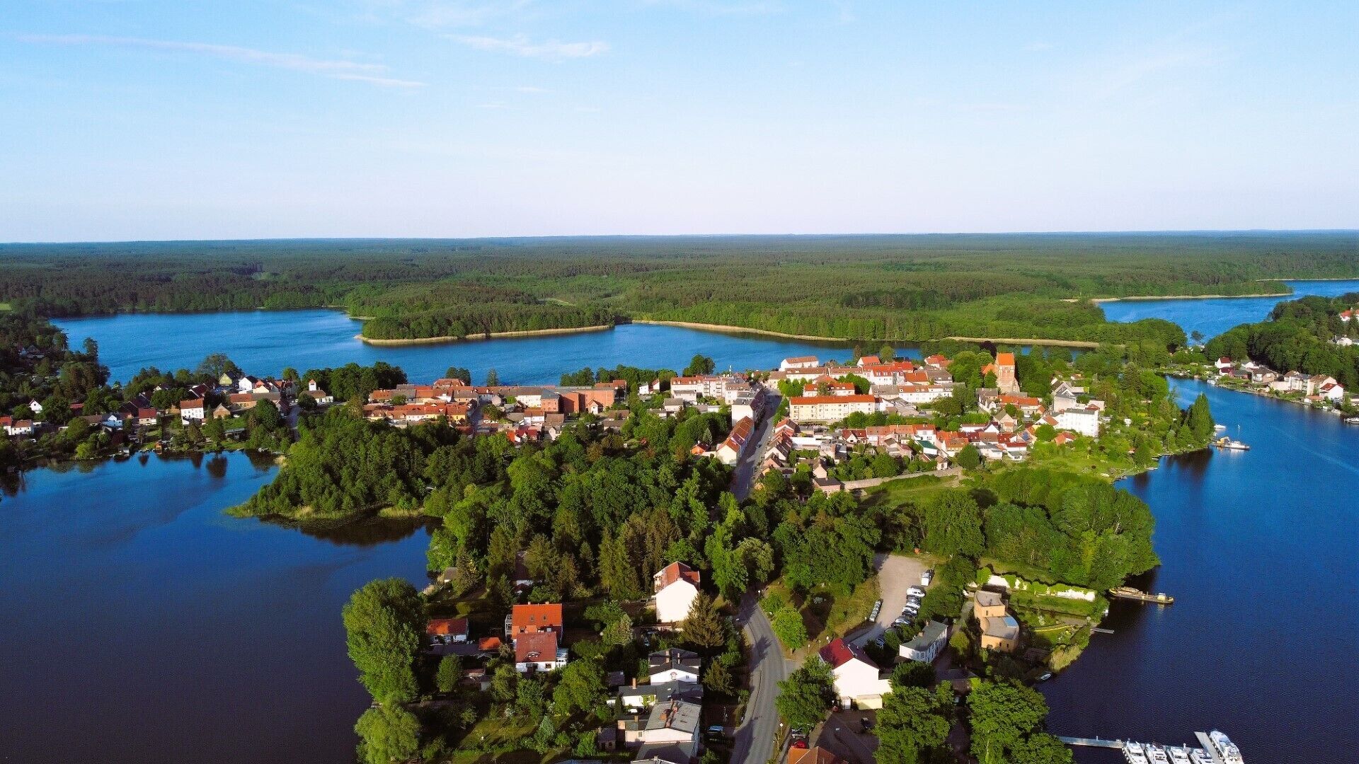 Vista aerea di un villaggio sul lago con case, una strada principale e un molo.