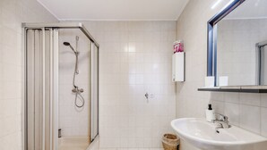 A modern bathroom with a glass-enclosed shower, a white sink, and a mirror above it. - Central charming apartment in the heart of Kulmbach (Kulmbach)