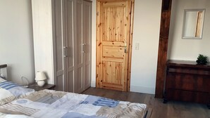A bedroom with a bed, a wooden wardrobe, a dresser, and a mirror on the wall. - Apartment 'Ferienwohnung Dg Rechts - Lychen' with Lake View, Shared Terrace and Wi-Fi (Lychen)