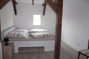 A bedroom with a bed, a nightstand, a lamp, and a window.