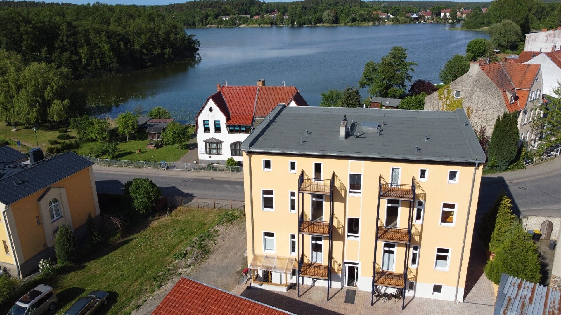 Ein mehrgeschossiges Gebäude mit flachem Dach, einem Balkon und Blick auf einen See.