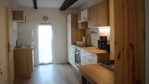 A kitchen with wooden cabinets, a coffee maker, and a door with a red stripe. - Apartment 'Ferienwohnung Dg Rechts - Lychen' with Lake View, Shared Terrace and Wi-Fi (Lychen)
