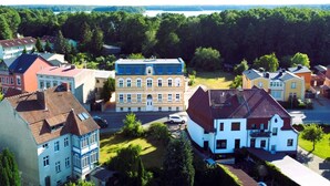 A residential area with houses, a central building with a blue roof, and a lake in the background. - Apartment 'Ferienwohnung Dg Rechts - Lychen' with Lake View, Shared Terrace and Wi-Fi (Lychen)