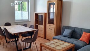 Ett rum med ett matbord i trä, stolar, en soffa och ett skåp.