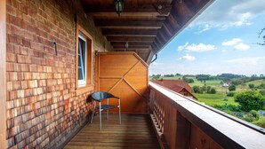 Ein Holzbalkon mit Backsteinmauer, Fenster und einem Stuhl.