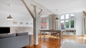 Ein geräumiges Wohnzimmer mit Kamin, Holzböden, einem Essbereich und großen Fenstern.