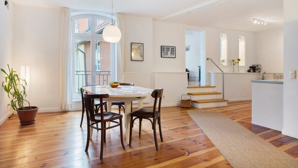 Ein modernes Interieur mit Essbereich, Holzboden, einer Treppe und einer Küchenzeile.