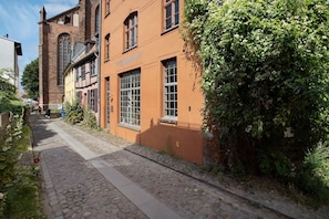 A cobblestone street with historic buildings, a church tower, and a pathway. - Apartment 'Alte Seifensiederei 2' with Wi-Fi (Stralsund)