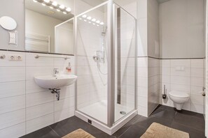 Ein modernes Badezimmer mit Duschkabine, Waschbecken, Toilette und Spiegel.