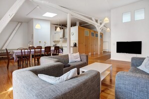 A modern living room with grey sofas, a white coffee table, and a dining area with wooden chairs and a table. - Holiday Apartment 'Alte Seifensiederei - Ferienloft' with Wi-Fi (Stralsund)
