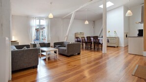 A spacious living area with a wooden floor, grey sofas, a white coffee table, and pendant lighting. - Holiday Apartment 'Alte Seifensiederei - Ferienloft' with Wi-Fi (Stralsund)