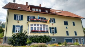 A two-story building with a balcony, large windows, and a tiled roof. - Apartment 'Donnerberg' with Shared Terrace, Shared Garden and Wi-Fi (Ühlingen-Birkendorf)