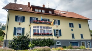 A two-story building with a balcony, large windows, and a tiled roof. - Apartment 'Hermanschau' with Shared Terrace, Shared Garden and Wi-Fi (Ühlingen-Birkendorf)